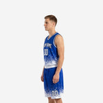 Side view of royal blue and white sublimated travel basketball uniform set showing pixel scatter hem transition on jersey and shorts