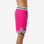 Side view of custom pink travel team basketball shorts showing V-notch chevron hem detail, side split, and white-black striped waistband