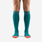 Custom turquoise soccer socks with coral heel and toe worn by adult male model, front view showing geometric diamond cuff pattern