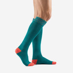 Custom turquoise soccer socks in teal with coral contrast toe block, side view showing full knee-high length on adult male model