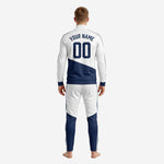 Close-up of custom white navy soccer tracksuit jacket with stand collar, crimson accent bar, and sublimated team logo zone