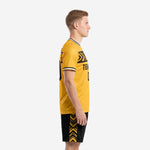 Custom yellow soccer uniform side view showing Athletic Gold jersey with black sublimated chest band and black shorts with gold chevron side panels