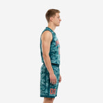Side view of teal digital camo custom youth basketball uniforms showing V-neck jersey armhole binding and matching shorts with vertical teal stripe side panels