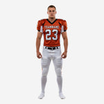 Custom youth tackle football uniforms in orange and white with black trim, arched team name, front number 23, and matching white pants with orange side stripe - front view