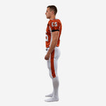 Left-side view of custom orange football uniform showing sleeve number placement, black shoulder accents, and full-length orange pant stripe on white pants
