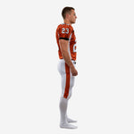 Side view of orange and white custom sublimated football uniform showing white triangular side panels, black sleeve cuffs, and orange leg stripe on white pants