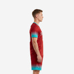 Custom red soccer uniform side view showing teal gradient fade on sleeve cuffs and shorts hem