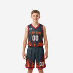 Front view of flame-pattern red and black youth basketball uniforms showing arced team name and front number on charcoal jersey and matching shorts