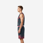 Side view of charcoal travel basketball uniform showing V-neck binding, armhole trim, and red halftone fade at shorts leg hem
