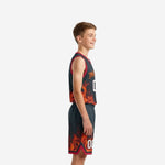 Side view of custom red and black youth basketball uniform set showing red armhole binding and flame graphic on jersey and shorts