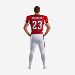 Reverse side view of sublimated red football jersey and white pants uniform showing sleeve seam detail and full-length pant stripe