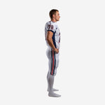 Side view of custom white and navy American football uniform showing navy jersey side panel and dual red-and-navy pant stripe