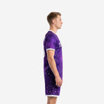 Side view of custom purple soccer uniforms on male model showing star-burst galaxy pattern across jersey and shorts