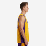 Adult male model wearing custom gold basketball jersey with purple side panels, crew neckline with white binding, and bold purple front number - front view
