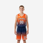 Front view of orange youth basketball uniforms with gradient fade to navy, white V-neck binding, arched team name, and matching shorts on a youth boy model