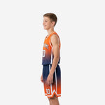Opposite side view of sublimated orange and navy youth basketball uniform showing contrast white armhole binding and shorts side stripe on a youth boy model