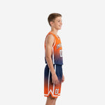 Side view of custom orange and navy gradient youth basketball uniform set showing white side panel and shorts chevron hem detail on a youth boy model