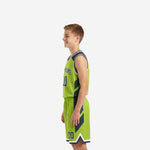 Side view of lime green custom youth basketball uniform set showing charcoal angular panel design on jersey and shorts leg
