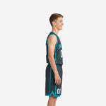Custom grey youth basketball uniforms charcoal V-neck jersey with teal binding and arched team name on youth player front view