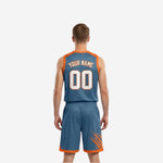 Steel blue and orange reversible basketball uniform side view showing armhole binding and slash-mark sublimation on the shorts leg panel