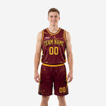 Front and back view of maroon and gold basketball uniforms with gold lightning bolt side panel and sublimated star-splatter detail on jersey and shorts