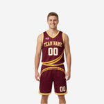 Custom maroon and gold reversible basketball uniforms front view showing maroon jersey with gold diagonal swoosh stripe and matching shorts on adult male model