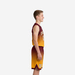 Custom maroon to gold gradient youth basketball jersey with arched team name and matching sublimated shorts, front view on youth boy model