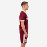 Side view of maroon sublimated soccer uniform kit with cream sleeve cuffs and side stripe shorts