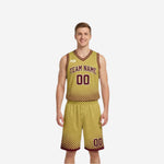 Gold side of the maroon and gold reversible basketball uniform showing maroon arched team name, maroon numbers, and halftone dot fade on jersey and shorts