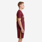 Left side view of maroon soccer uniform set showing Vegas Gold side stripe on shorts and geometric cross-hatch pattern on jersey