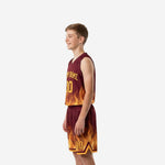 Opposite side view of custom maroon youth basketball uniform set showing full flame graphic on jersey hem and lower shorts panel in orange and gold