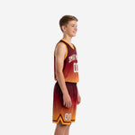 Side view of maroon and orange sublimated youth basketball uniform set showing gradient fade gold armhole binding and matching shorts with chevron hem accent