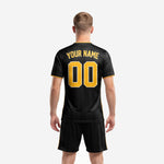 Close detail of all black sublimated soccer jersey with Athletic Gold team name lettering and front number on pinstripe body