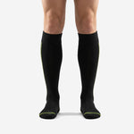 Mens black and green soccer socks front view showing jet black body with neon green calf accent lines and ribbed cuff