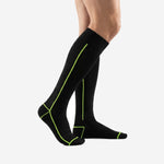 Mens black and green soccer socks side angle view displaying neon green geometric stitching along calf panel and heel