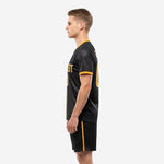 Right side view of men's custom black and gold soccer kit highlighting chevron texture and gold outer-seam shorts stripe
