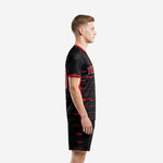 Custom black and red soccer uniform left side view showing full stripe design and red crew neck trim on male model