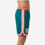 Side view of mens custom basketball shorts showing coral-red side stripe with two white pinstripes running full length of the teal leg panel