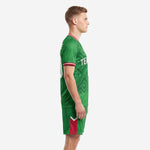 Side view of mens custom Kelly Green soccer uniforms online showing V-neck collar, red sleeve trim, and red side panel on shorts