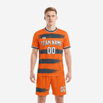 Men's custom orange and graphite soccer outfit with brushstroke stripe pattern, front view of full 2-piece kit