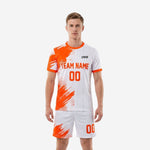 Custom orange and white men soccer jersey detail showing brush-stroke halftone sublimation print and crew neck orange trim