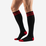 Custom red and black striped soccer socks over-the-calf length on adult male model at an angle
