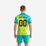 Close detail of custom teal and neon yellow soccer uniform jersey showing chest team name, front number, and black crew-neck trim