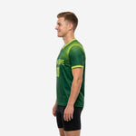 Mens custom training jersey in Forest Green with Neon Green dot-burst pattern fading toward lower hem, right side view showing sleeve cuff trim
