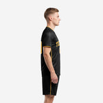 Side view of mens all black soccer uniform showing Athletic Gold side stripe on shorts and sleeve cuff trim detail