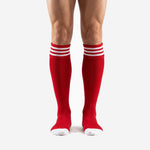 Mens red soccer socks with triple white stripe cuff band, front view on adult male model