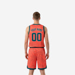 Side view of coral-orange reversible basketball uniform showing teal V-neck binding and shorts number placement on lower left leg