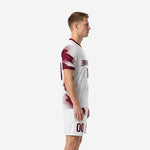 Custom maroon and white men's soccer team uniforms side view showing halftone dot-fade panel design on jersey sleeve and shorts leg