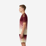 Right side view of men's soccer team uniforms in maroon-to-cream fade with gold side stripe detail on jersey and shorts