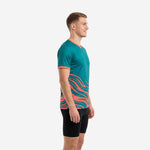 Mens teal soccer training jersey with coral wave graphic sweeping across lower body, left side view